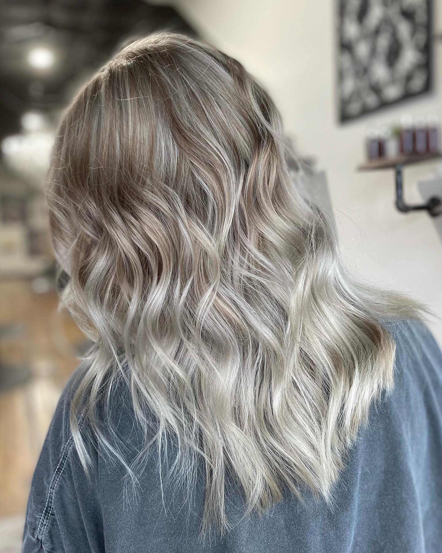 Icy blonde balayage with a soft shadow root on shoulder-length waves, colored at GreenRoom Salon & Spa, Greencastle, Indiana